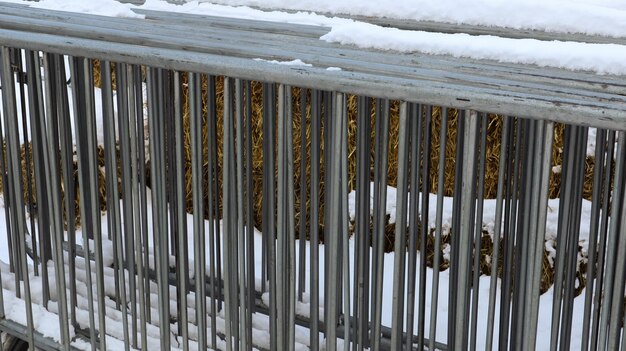 Een draagbaar metalen evenementenhek wordt in de winter op één plek op de kermis in de sneeuw buiten gehouden. Grijze roosters voor het rommelig maken van de ruimte en het organiseren van de wachtrij voor het evenement.