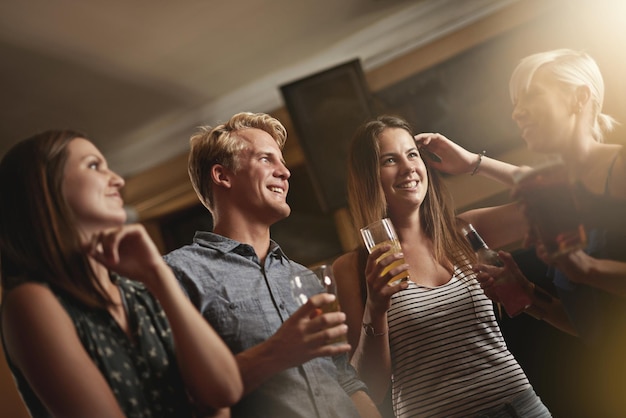 Een drankje en een lach delen Shot van een groep vrienden die aan het genieten zijn in de bar