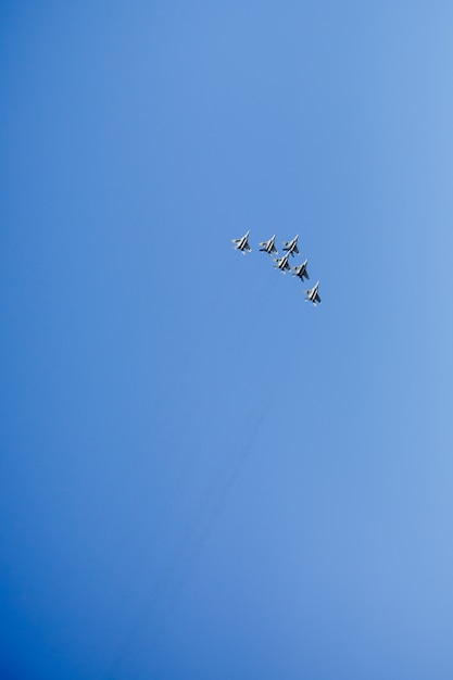 Een driehoekige formatie van een groep van zes Russische militaire straaljagers die hoog in de blauwe lucht vliegen