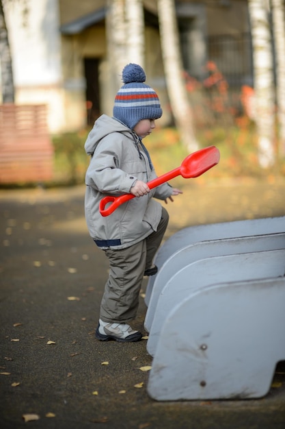 Een driejarige jongen met een schop op de speelplaats