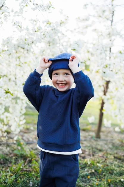 Een driejarige jongen rent door een bloeiende tuin Vrolijk emotioneel kind loopt in het park