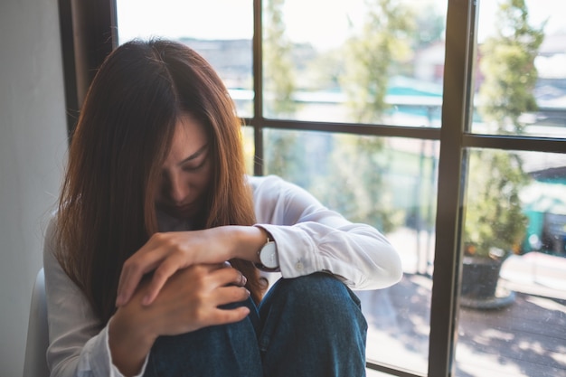 Een droevige jonge vrouw die alleen in de kamer zit