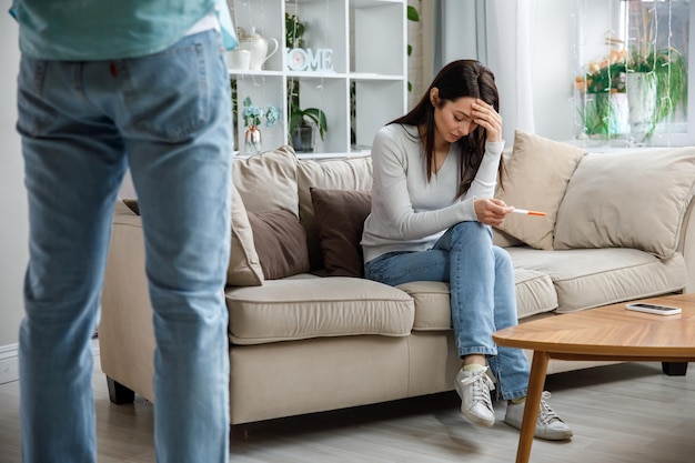 Een droevige jonge vrouw houdt een zwangerschapstest in haar hand Het concept van ongewenste zwangerschap