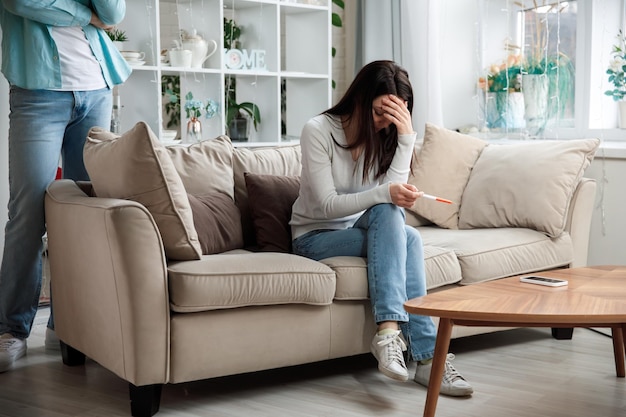 Een droevige jonge vrouw houdt een zwangerschapstest in haar hand het concept van ongewenste zwangerschap