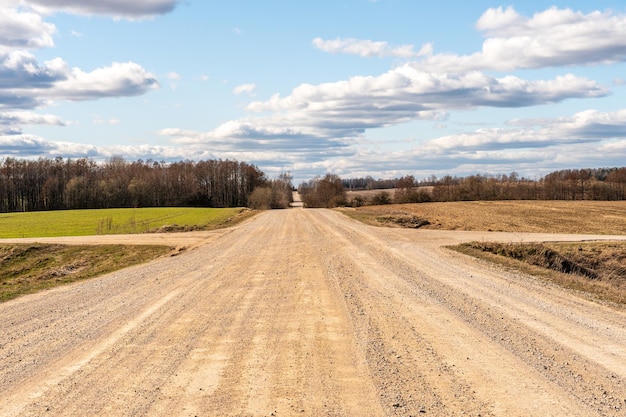 Een droge zandweg loopt door een veld onder de brandende zon en wolken Onverharde weg buiten de stad in het dorp Droog klimaat op aarde