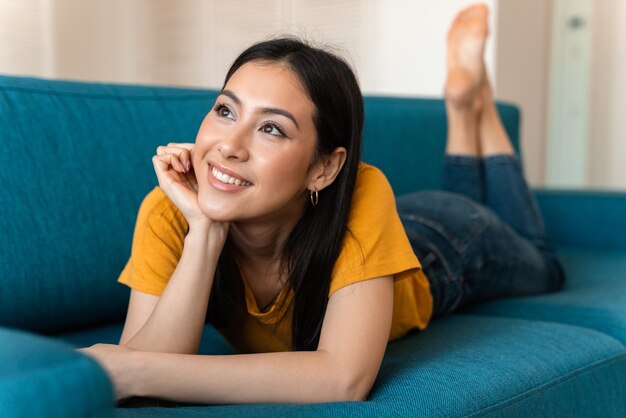 een dromende vrij optimistische brunette jonge vrouw op de bank binnenshuis thuis.