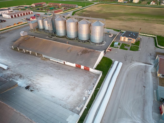 Een drone vliegen over zilveren silo's op een agro-fabriek voor het verwerken, drogen, reinigen en opslaan van landbouwproducten, meel, granen en graan Grote ijzeren vaten graan vanuit de lucht