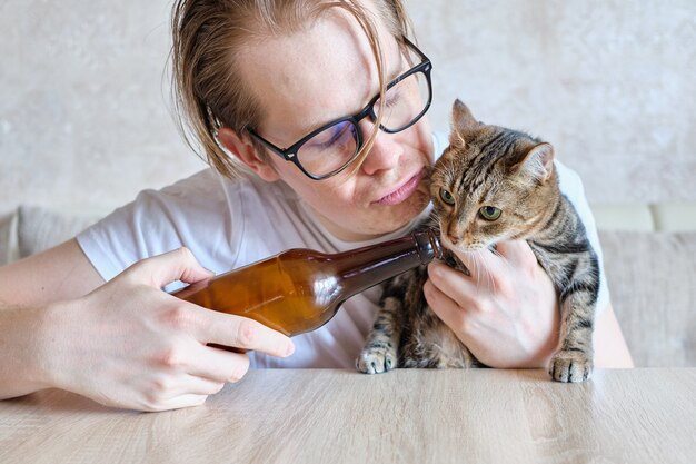 Een dronken man biedt zijn kat een drankje aan.