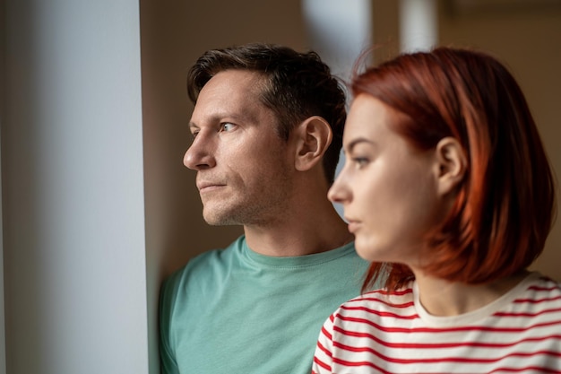 Een duitse man en vrouw van middelbare leeftijd kijken uit het raam en denken dat ze een relatieprobleem hebben.