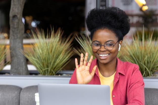 Een duizendjarige Afro-Amerikaanse vrouw werkt of een student praat via videocommunicatie vanaf een laptop