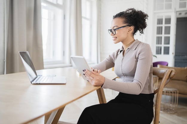 Een duizendjarige vrouw werkt op kantoor aan een nieuw project in een financieel bedrijf en gebruikt een laptop op tafel