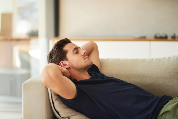 Een dutje doen Bijgesneden opname van een knappe jonge man die thuis op zijn bank rust