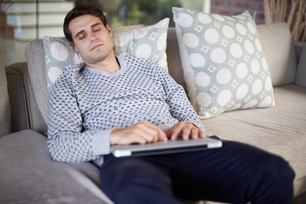 Een dutje doen na een training met zijn vingers shot van een man die op zijn bank slaapt met zijn laptop op schoot