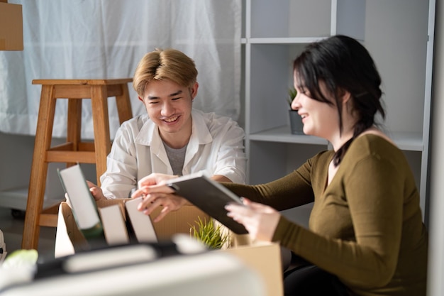 Een echtpaar dat gelukkig boeken en decoratieartikelen uitpakt in hun nieuwe huis en ideeën en glimlachen deelt