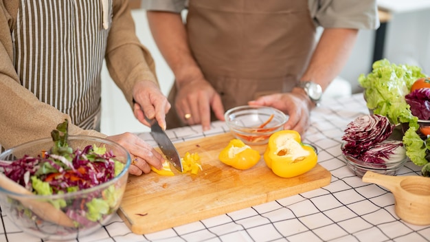 Een echtpaar kookt in de keuken een vrouw hakken een zoete peper terwijl haar man naast haar helpt