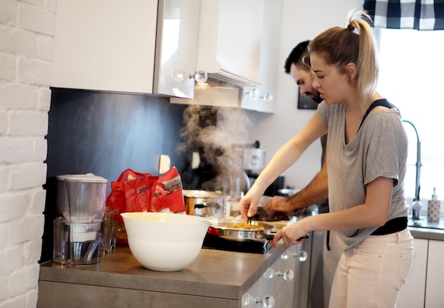 Een echtpaar kookt thuis in de keuken.