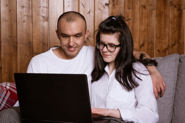 Een echtpaar om thuis te zitten op de bank met een laptop om goederen online te bestellen