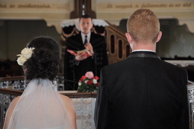 Foto een echtpaar staat voor de priester tijdens de huwelijksceremonie in de kerk