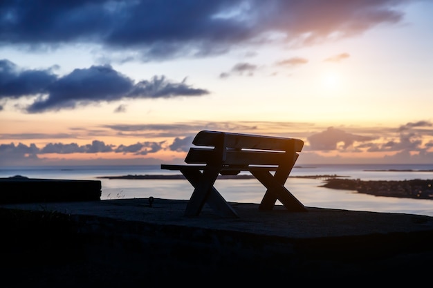 Een eenzame houten bank staat bovenop een berg. Zonsondergang avondtijd