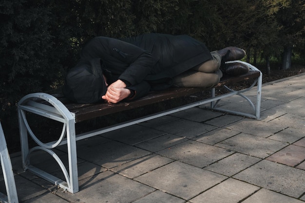 Een eenzame man, dakloos en overstuur, slaapt op een bankje in het park.