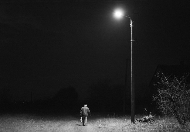 Een eenzame man gaat 's nachts onder een lantaarn