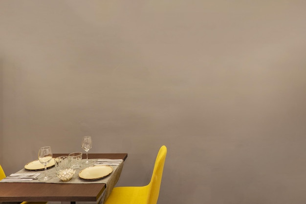 Een eenzame restauranteettafel met vast servies aan een effen grijze muur