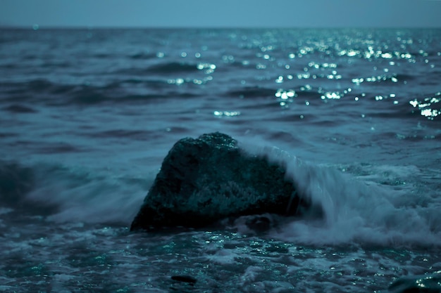 Een eenzame steen gewassen door de zee verlicht door licht