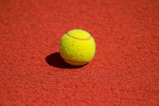 Een eenzame tennisbal op een rode zandbank