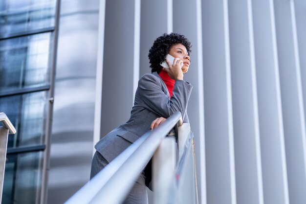 Een elegante Afro-Amerikaanse vrouw die de telefoon gebruikt in een kantoorgebouw op het werk