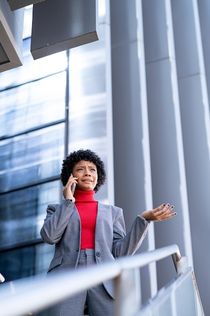 Een elegante Afro-Amerikaanse vrouw die de telefoon gebruikt in een kantoorgebouw op het werk