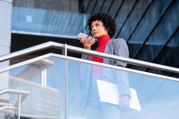 Een elegante Afro-Amerikaanse vrouw die de telefoon gebruikt in een kantoorgebouw op het werk