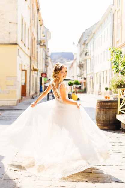 Een elegante bruid die danst op de straat van de stad tussen de gebouwen van een goede zonnige dag