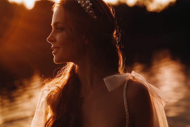 Een elegante bruid in een witte jurk geniet van de natuur bij zonsondergang. Model in een trouwjurk in de natuur in het park. Wit-Rusland