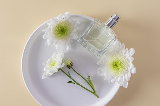 Een elegante fles met een cosmetisch parfum of spray op een witte keramische plaat tussen witte bloemen bovenaanzicht Een lege lay-out