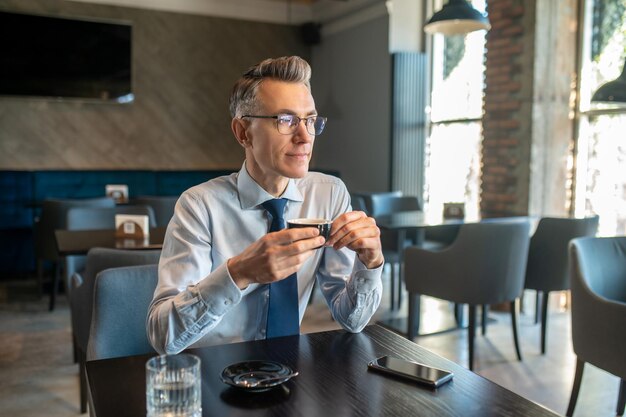 Een elegante man met een bril die in een café zit