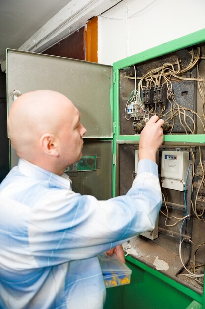 Een elektricien aan het werk met een steeksleutel, draai de schroef in de elektrische doos vast