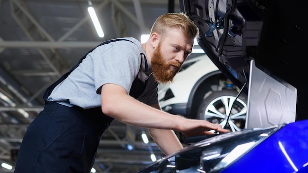 Een elektricien tijdens het oplossen van problemen in een auto met behulp van professionele apparatuur bij een servicestation