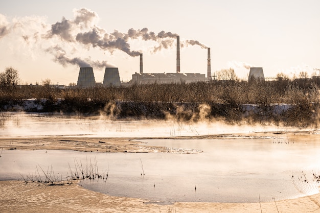 Een energiecentrale laat verontreinigende stoffen vrij in de lucht en in een waterlichaam. milieuvervuiling