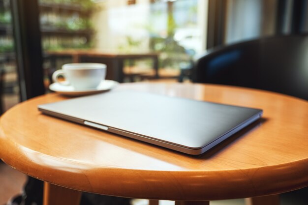 Een enkele laptopcomputer met een koffiekopje op houten tafel