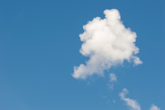 Een enkele witte wolk in de blauwe lucht