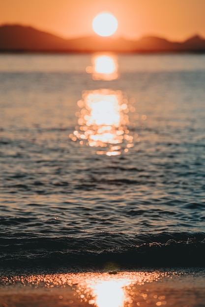 Een enorme zonsondergang over de eilanden die in de lente reflecteert over de oceaan met de zon en de getijden op het strand over het zand in de lente, op kleurrijke tinten met kopie ruimte