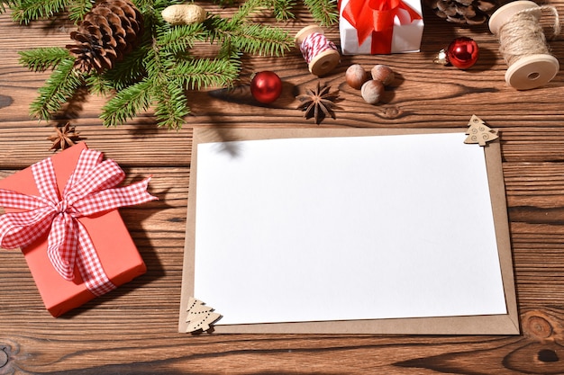 Een envelop en een blanco vel papier op een houten tole met kerstversiering. Gelukkig nieuwjaar. Ruimte kopiëren. Plat lag, bovenaanzicht.