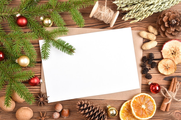 Een envelop en een blanco vel papier op een houten tole met kerstversiering.