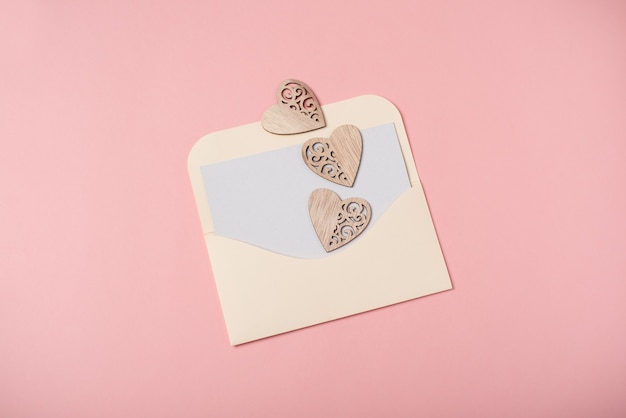 Een envelop met een blanco vel en houten hartjes. Valentijnsdag concept.