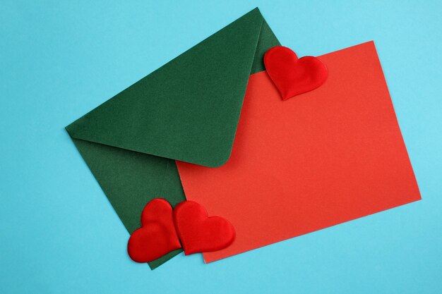 Een envelop met een vel en harten ligt op een blauw voor het schrijven van een romantische brief.