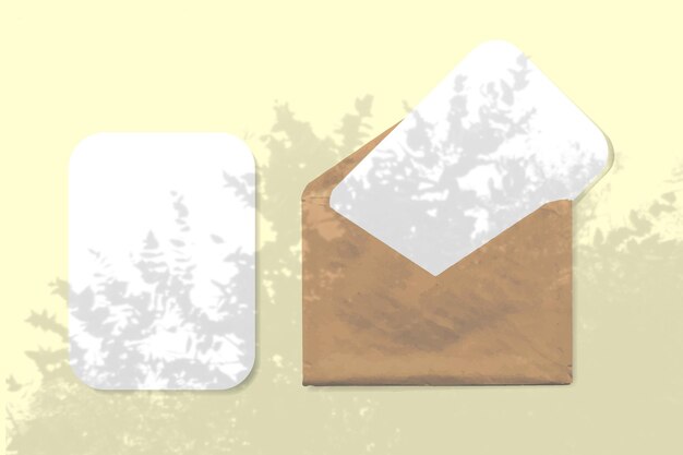 Een envelop met twee vellen gestructureerd wit papier op gele achtergrond mock-up met een overlay van