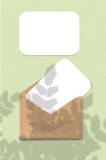 Een envelop met twee vellen getextureerd wit papier op een groene achtergrond mock-up met een overlay van t