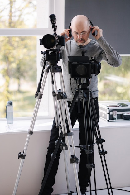 Foto een ervaren cameraman maakt een video in de studio man gebruikt camera en statieven professionele audioapparatuur