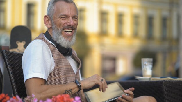 Een Europese man van middelbare leeftijd werkt privé met een tablet in een straatcafé