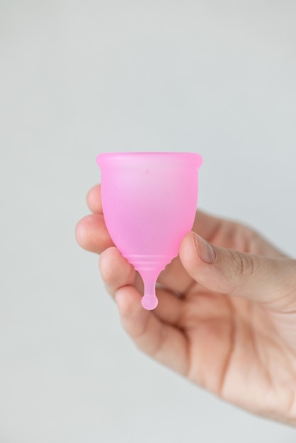 Een Europese vrouw houdt een roze menstruatiecup gemaakt van siliconen in haar handen hygiëne en verzorging voor vrouwen